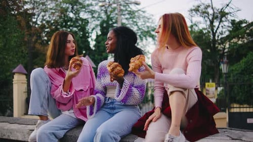 Friends Enjoying Croissants Together in Urban Setting