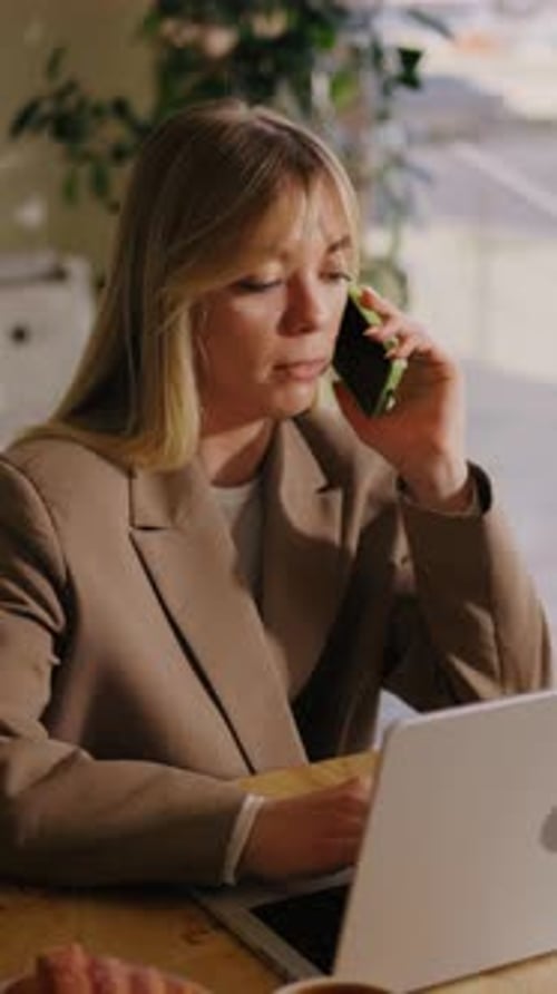 Woman Working on Laptop and Talking on Phone