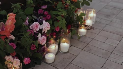 Candles Stand Next to Flowers on the Ground Creating a Carefree Atmosphere Next to the Wedding