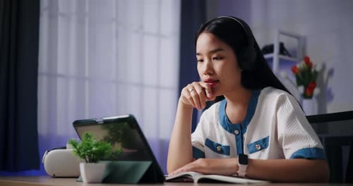 Young Woman Studying Using Tablet and Notebook at Home