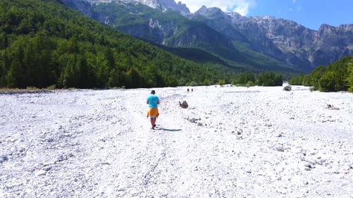 A young hiker walking along the dry river in summer through the Valbona valley, Theth national park,
