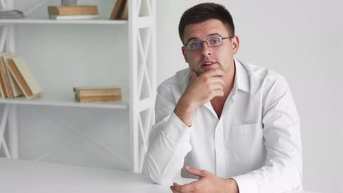 Man Thinking at Desk in Bright White Room