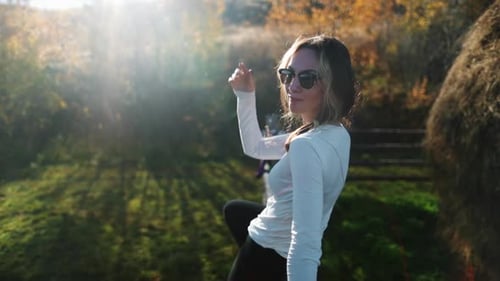 Woman Relaxing in Sunlight on Farm Fence