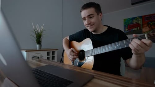 Young Man Playing Acoustic Guitar at Home
