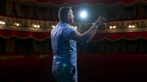Middle age male entertainer, presenter or actor on stage. Public speaker gives performance.