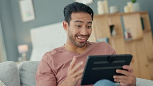 Man Celebrates Success While Using Tablet at Home
