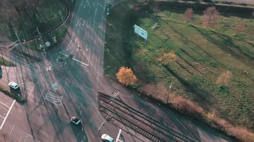 Flying over crossroad of a technology park with cars passing by with sunlight and shadow of surround
