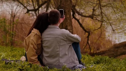 Young Couple Taking Selfie by Lake in Autumn