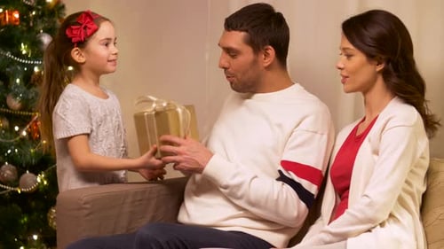 Family Exchanging Christmas Gifts by Christmas Tree
