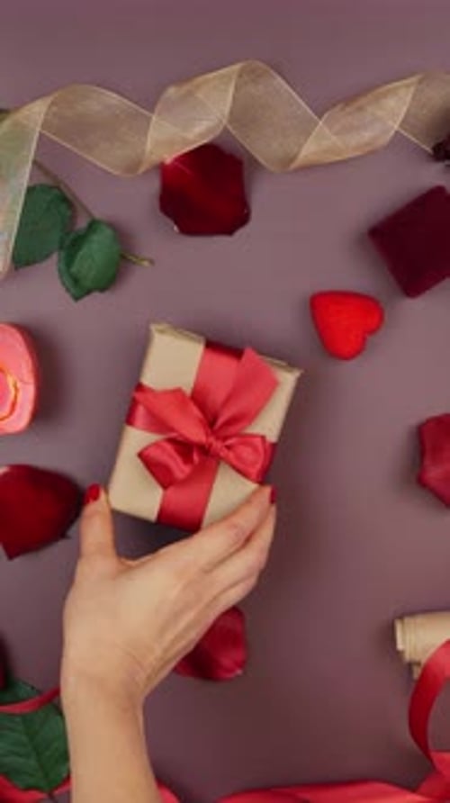 Male giving wrapped box with tied red bow to female, close up. Vertical video