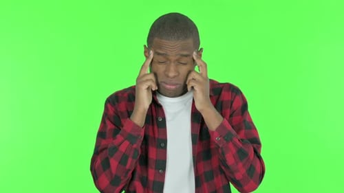 African Man Having Headache on Green Background