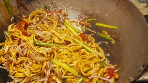 Stir frying noodles with vegetables in a wok