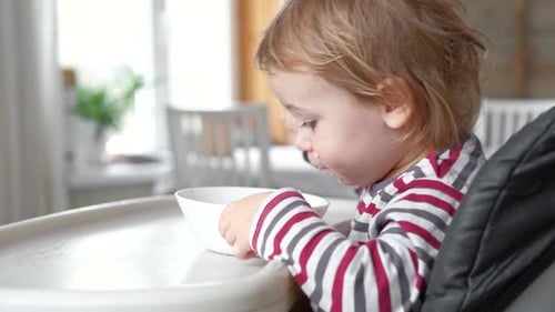 Child Eating Cereal in a High Chair