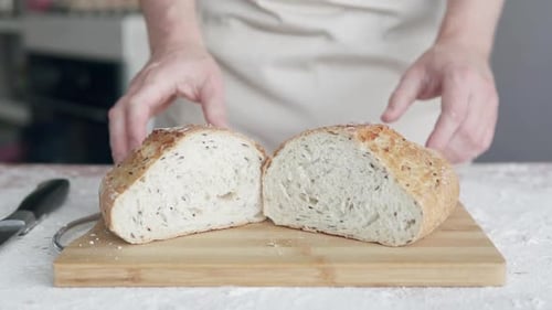 A professional baker cuts fresh and crispy freshly baked bread with a knife.