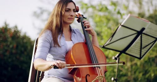 4k video footage of a beautiful young woman playing a string instrument outdoors