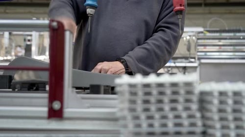 A technical worker in a production workshop. A technician attaches parts to the metal base of a lamp