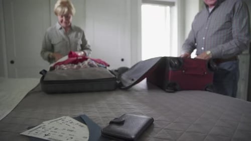 Senior Couple Packing Suitcases for Travel in Bedroom