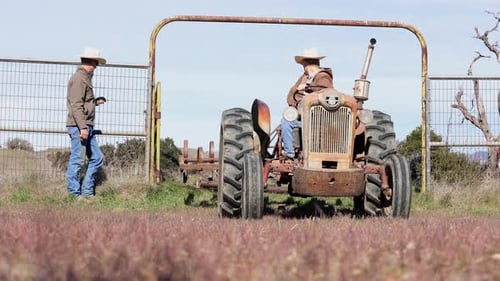 Cowboys Working on Harrow Tractor in Horse Arena