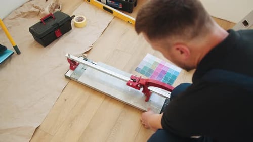Man Cuts Floor Tile with Manual Tile Cutter