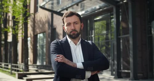 Confident Businessman in Formal Clothes Crossing Hands While Standing Near Modern Office Serious
