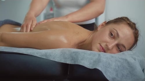 Girl Happy Relaxing Lying Oil Massage with Hands of Young Woman Back in Spa Salon