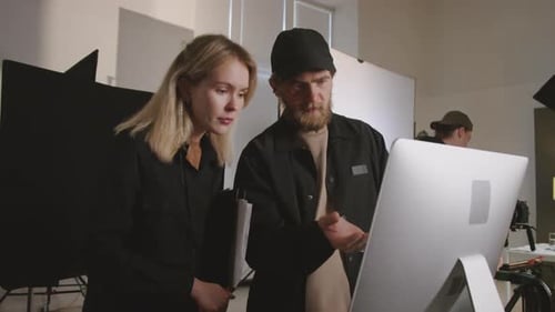 Director and Producer Looking at Filmed Footage on Monitor in Studio