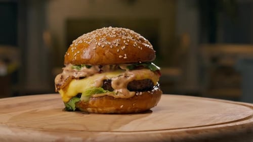 A close-up of a juicy burger with beef patty with vegetables and cheese cooked in the kitchen