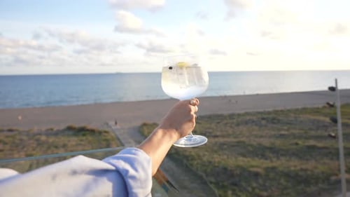 Cocktail gin and tonic in a terrace held by a woman with beautiful and amazing sea views landscape.