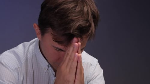 Man with hands clasped in front of face