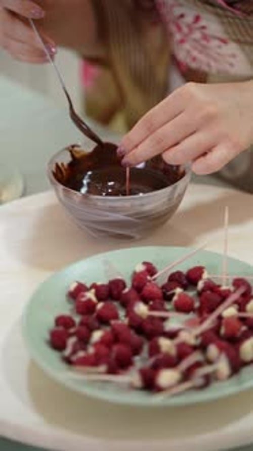 Woman Dipping Raspberry Skewers in Melted Dark Chocolate