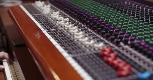 Man in a control room of a recording studio moving a fader with a Toft console / Professional record