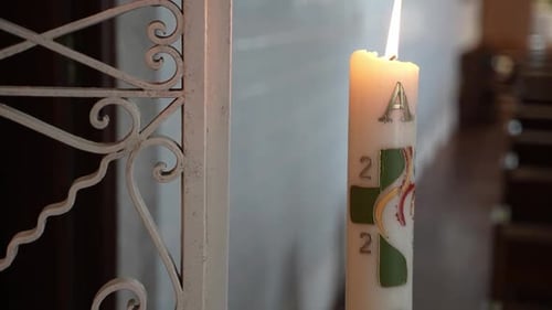 Paschal candle with symbols and burning flame inside church - closeup