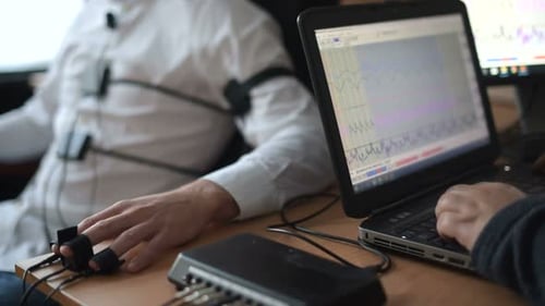 Work in progress. Suspicious man passes lie detector in the office. Asking questions.