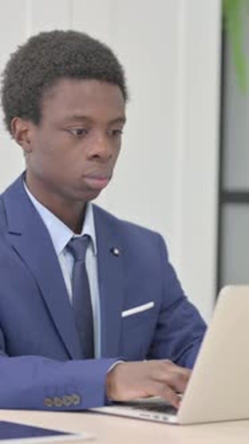 Young Man in Suit Working at a Laptop