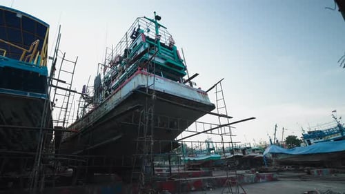 A Large Fishing Boat in the Process of Repair and Maintenance is Leaning on a Scaffold in a Shipyard