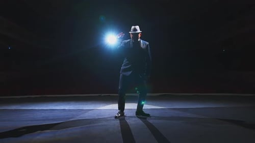 Artista bailando en escena. Hombre teatral con elegante traje y sombrero actuando en el escenario en el centro de atención.
