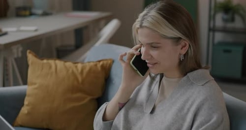 Woman on Couch Using Laptop and Talking on Phone
