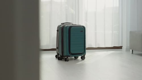Les valises de voyage se trouvent près d'une fenêtre dans une pièce lumineuse aux rideaux blancs