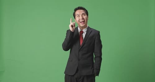 Asian Business Man Thinking Then Raising Her Index Finger While Standing In Green Screen Studio