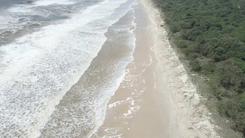 Foamy Waves Washing Up On The Sandy Shore Of Beach After The Storm. - aerial descend