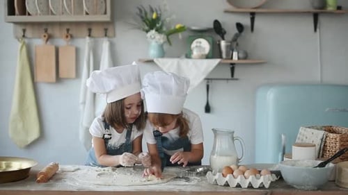 Zwei Kinder in weißer Kochuniform backen in der Küche Formen aus Teig