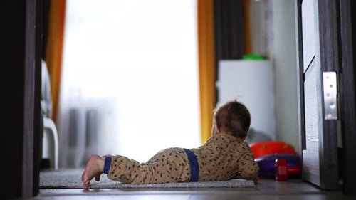Das aktive Baby liegt auf dem Teppich, steht auf und kriecht zur Kamera.