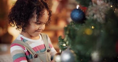 Happy kid, girl and decorate on Christmas tree for festive, holiday and celebration in home