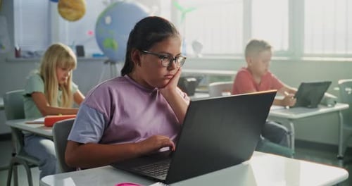 Computer Science Lesson Primary School Girl Sitting at Desk Using Laptop in Classroom