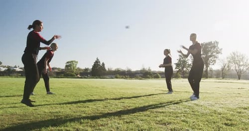Playing cricket on field, women practicing catching and throwing ball outdoors