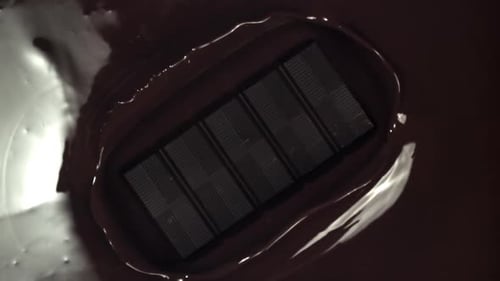 La barra de chocolate cae en el chocolate líquido fundido filmado con una cámara de alta velocidad a 1000 fps
