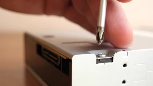 T17, Bei der Reparatur eines elektronisch Geräts wird eine Schraube mit einem Schraubenzieher herausgeschraubt.