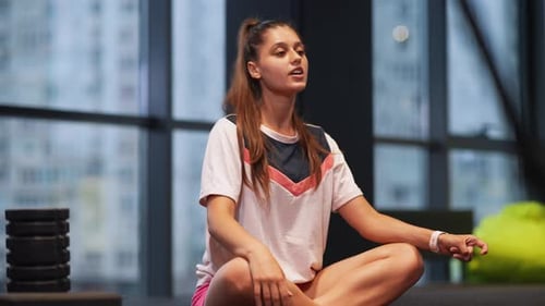 Woman Stretching Neck Sitting Cross-Legged in Gym