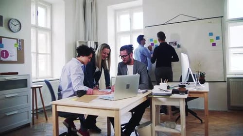 Group of Young Businesspeople with Laptop Working Together in a Modern Office