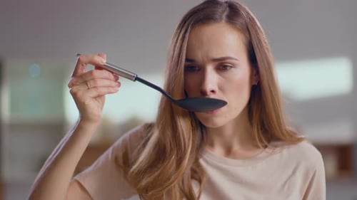 Woman Tries Food with Ladle in Kitchen